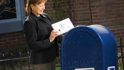 woman-places-package-us-postal-service-mailbox